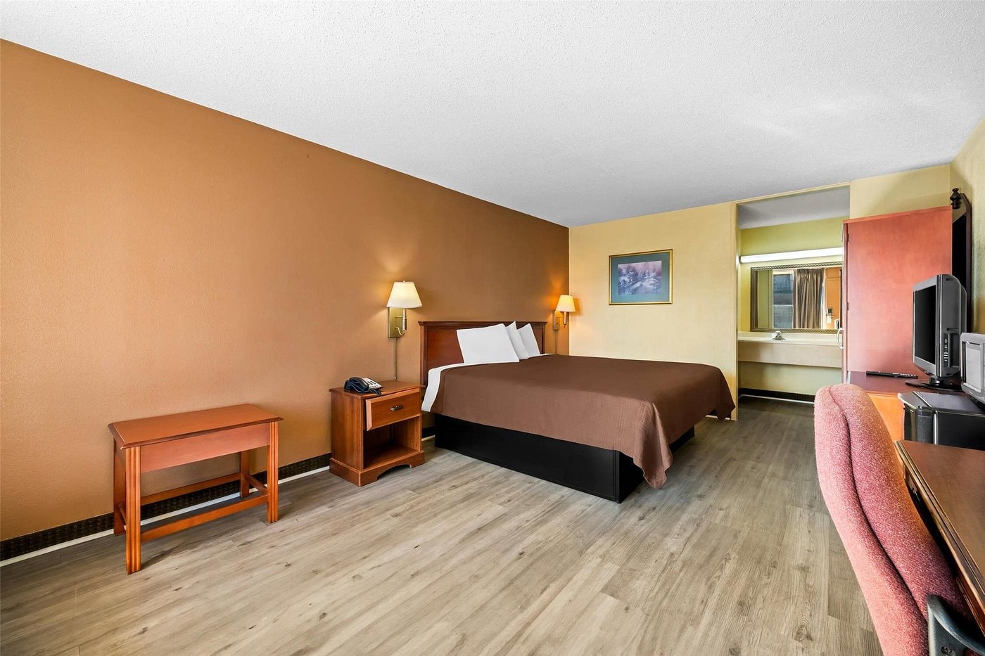 King room at Rodeway Inn Monroe — wall-mounted flat-screen TV, rolling office chair, work desk, microwave and mini fridge