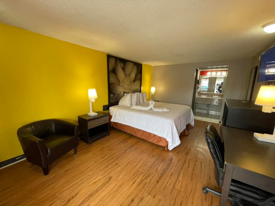 King room with yellow accent wall, leather chair, and wood floors